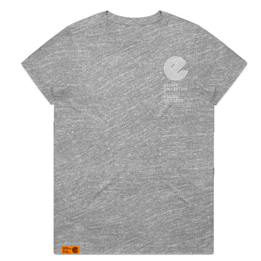 A heather gray short-sleeve t-shirt with a small white circular logo and text on the left chest, and a small orange tag near the bottom left hem, shown on a plain white background.
